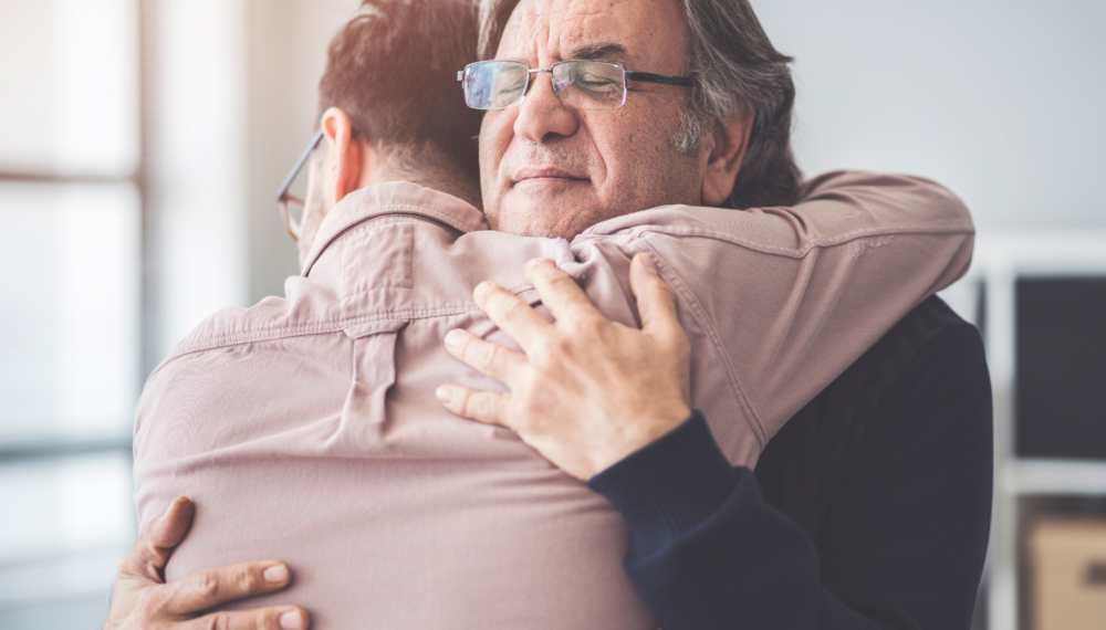 Older man hugging son in a moment of gifting a living inheritance.