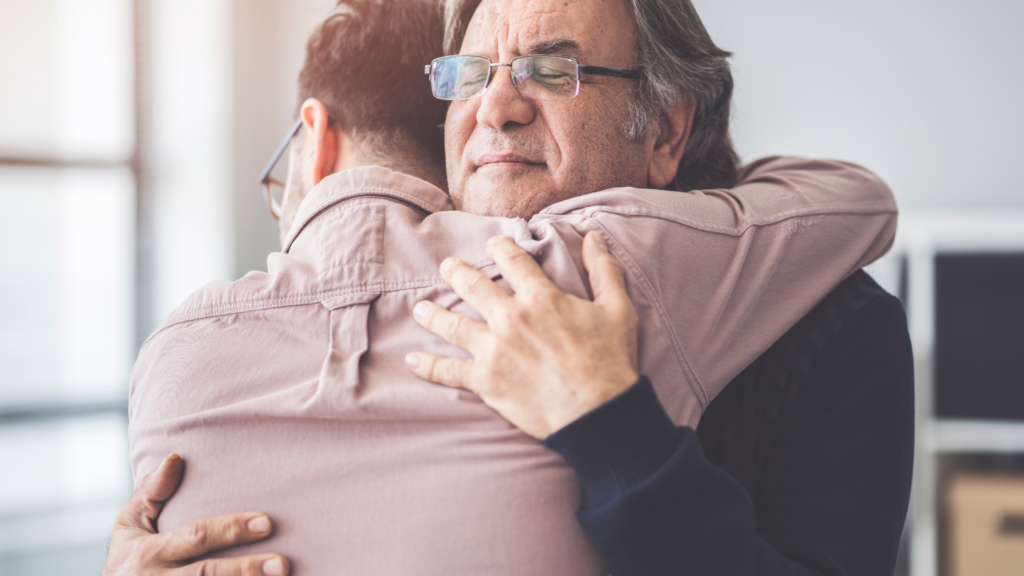 Older man hugging son in a moment of gifting a living inheritance.