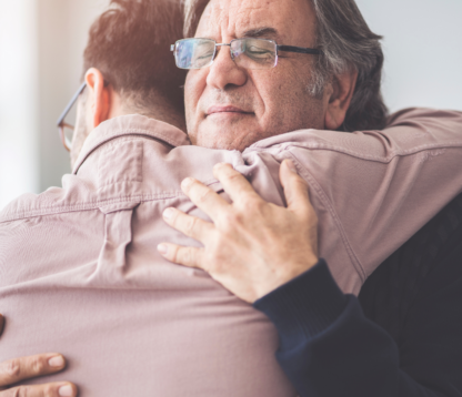 Older man hugging son in a moment of gifting a living inheritance.
