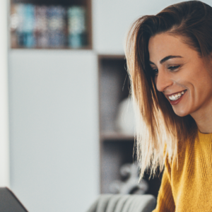 Woman looking at her laptop smiling as she reads remortgage guide