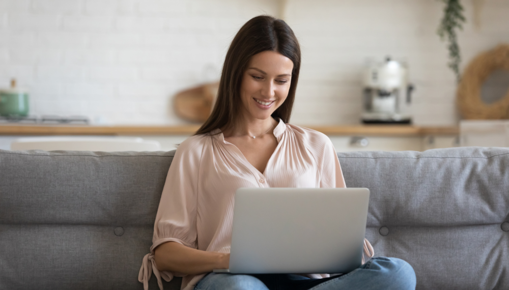 woman on sofa looking at her laptop smiling