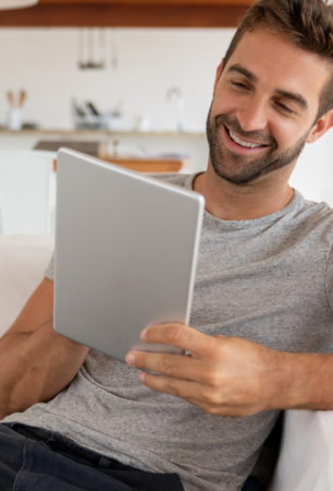 man smiling on sofa looking at his tablet