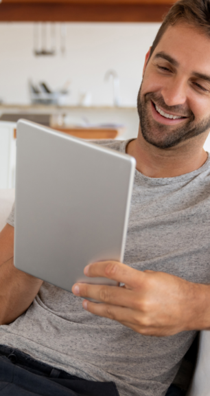 man smiling on sofa looking at his tablet