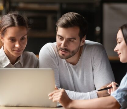 A young couple with a mortgage adviser looking at a laptop