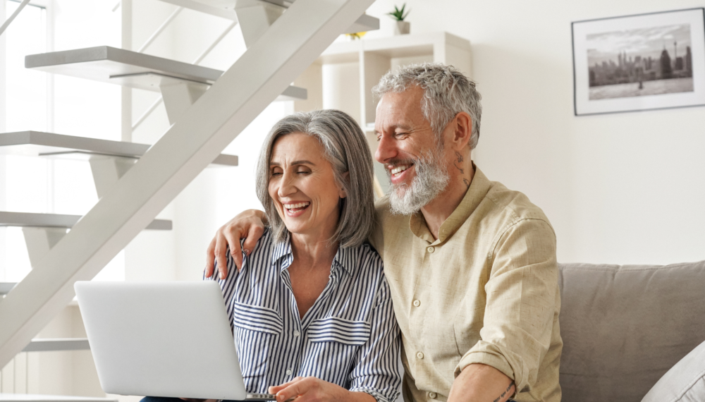 over 55 couple looking at their laptop and smiling