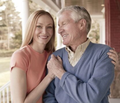 Smiling father and daughter by house