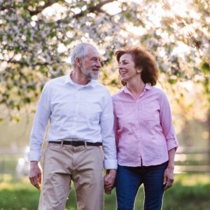 Happy couple over the age of 55 walking in gardens with blossom trees