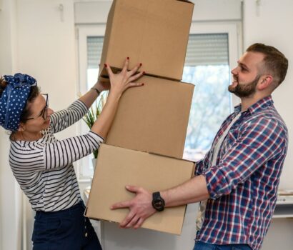 a man and woman moving house, holding boxes