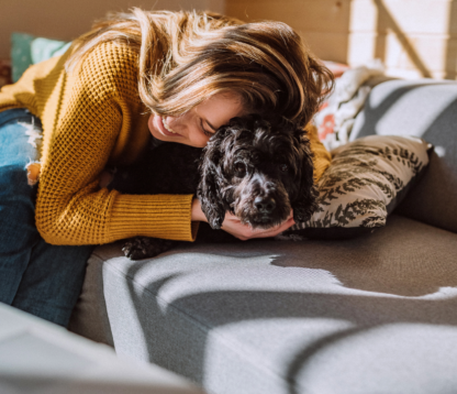 woman at home on the sofa cuddling their dog