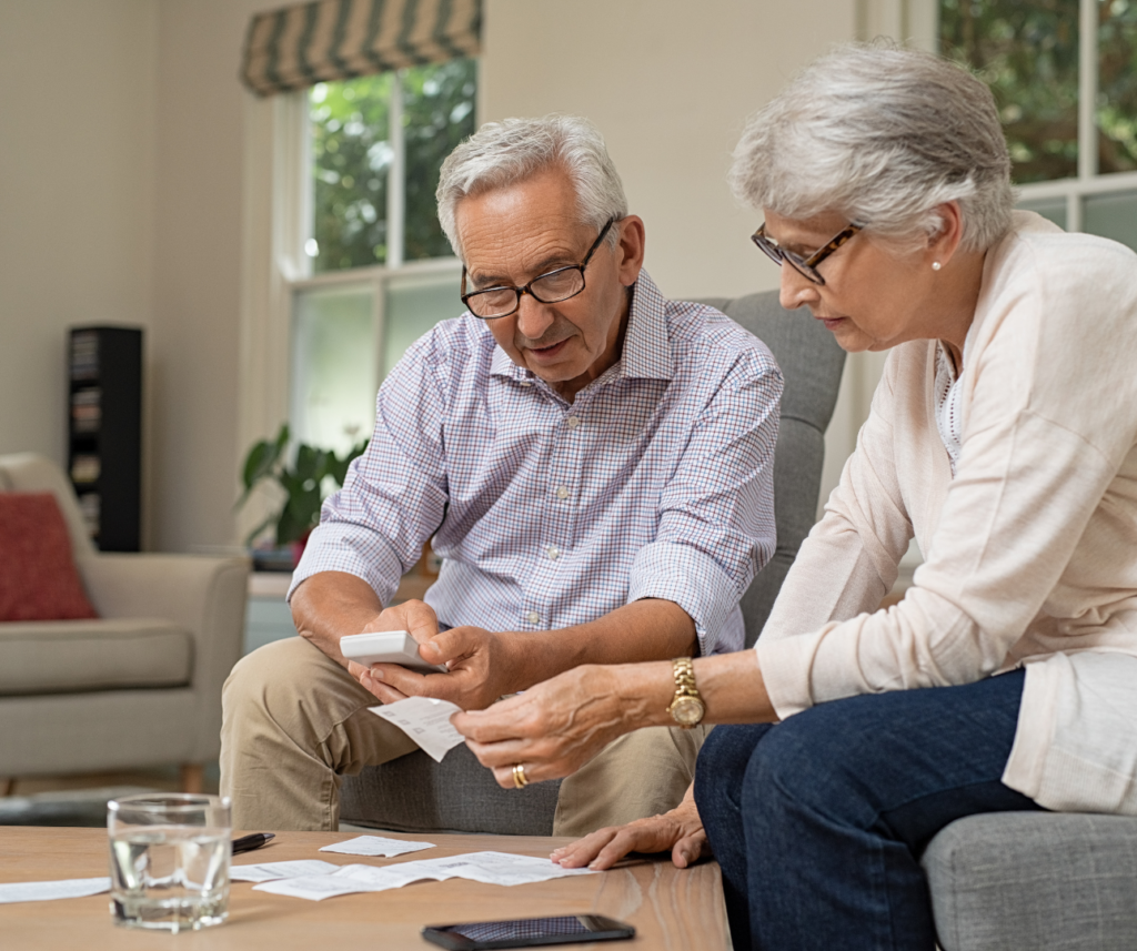 Elderly couple reviewing financial documents at home, symbolising careful planning, informed decision-making, and the importance of understanding asset implications in later life care funding.