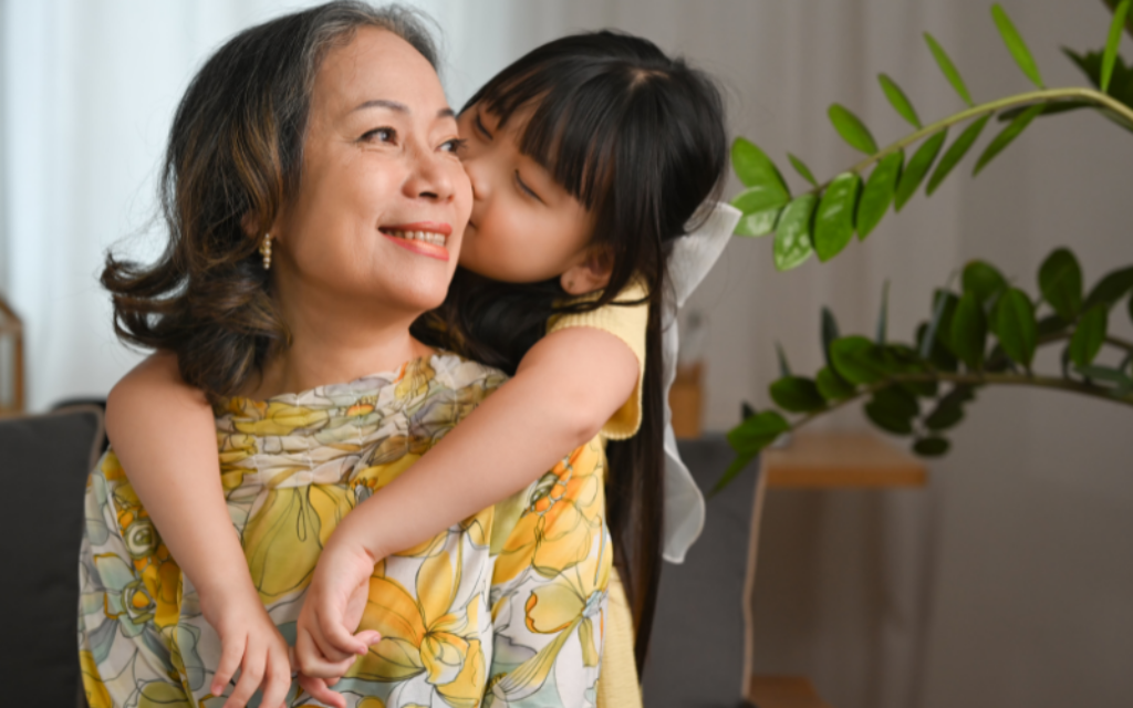 Smiling grandmother embraced by her young granddaughter, symbolising intergenerational gifting and legacy planning.