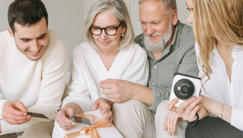 Happy multigenerational family gathered together, opening a gift, symbolising the benefits of a later life mortgage.