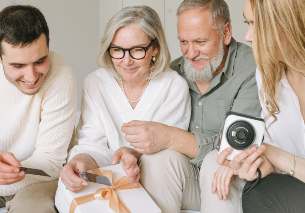 Happy multigenerational family gathered together, opening a gift, symbolising the benefits of a later life mortgage.