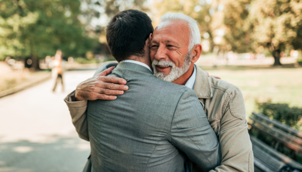 Older man warmly embracing a younger man outdoors, symbolising intergenerational support and thoughtful family planning.